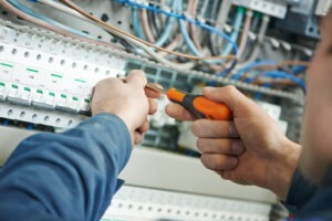 a close-up of a man holding a screwdriver on an electrical panel